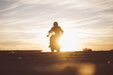 Silhouette of man riding custum motorcycle at sunset - OCMF00224