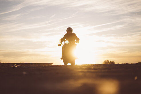 Silhouette eines Mannes auf einem Custum-Motorrad bei Sonnenuntergang - OCMF00224