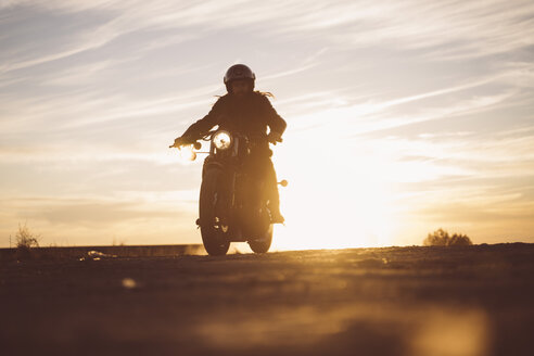 Silhouette eines Mannes auf einem Custum-Motorrad bei Sonnenuntergang - OCMF00225