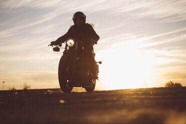 Silhouette eines Mannes auf einem Custum-Motorrad bei Sonnenuntergang - OCMF00226