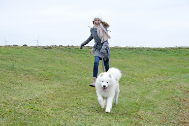 Lachendes Mädchen, das mit ihrem Hund auf einer Wiese läuft - ECPF00247