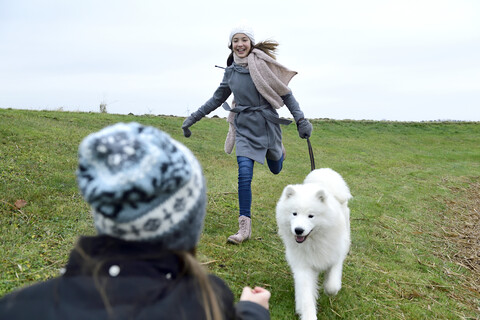 Zwei Mädchen haben Spaß mit Hund im Freien, lizenzfreies Stockfoto