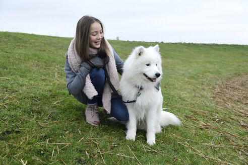 Glückliches Mädchen, das mit seinem Hund auf einer Wiese hockt - ECPF00249