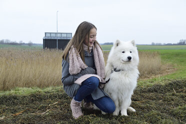 Glückliches Mädchen hockt auf einer Wiese neben ihrem Hund - ECPF00251