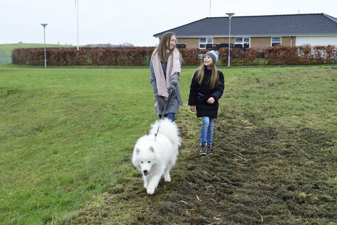 Zwei Schwestern spazieren mit Hund - ECPF00254