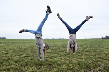 Two girls doing handstand on a meadow - ECPF00263