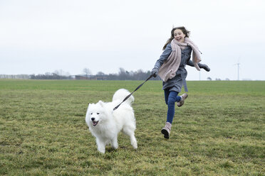 Lachendes Mädchen, das mit ihrem Hund auf einer Wiese läuft - ECPF00269