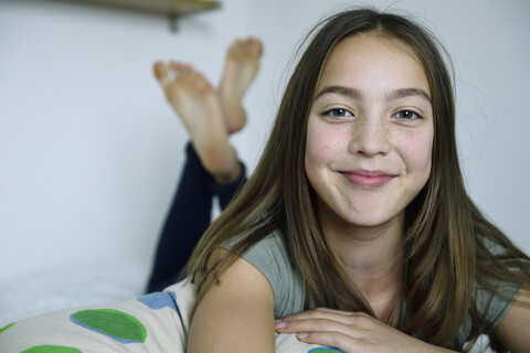 Porträt eines lächelnden Mädchens auf dem Bett liegend, lizenzfreies Stockfoto