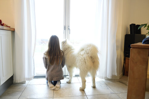 Rückenansicht eines Mädchens und ihres Hundes, die durch eine Balkontür schauen - ECPF00281