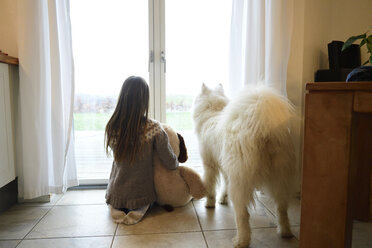 Rückenansicht eines Mädchens und ihres Hundes, die durch eine Balkontür schauen - ECPF00282