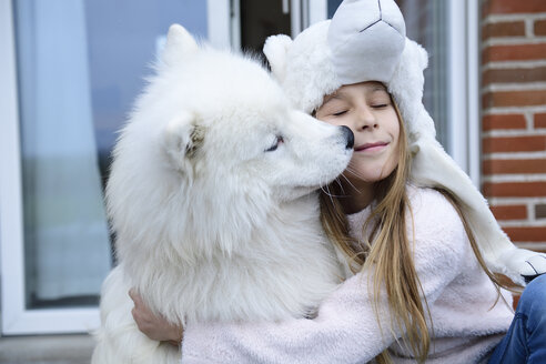 Mädchen, das ihren Hund auf der Terrasse umarmt - ECPF00285