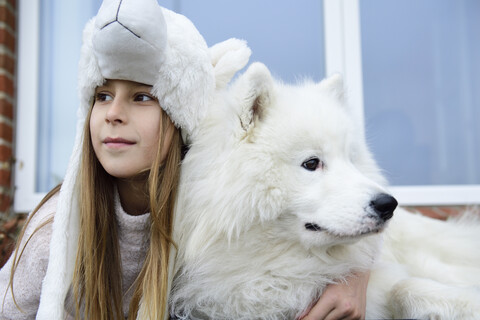 Porträt eines zufriedenen Mädchens auf einer Terrasse mit ihrem weißen Hund, lizenzfreies Stockfoto