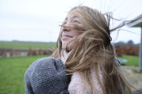 Portrait of smiling girl with blowing hair in winter looking up - ECPF00293