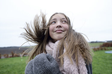 Porträt eines lächelnden Mädchens mit wehendem Haar im Winter, das nach oben schaut - ECPF00294