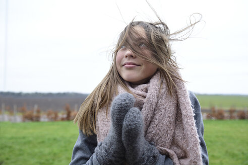 Porträt eines lächelnden Mädchens mit wehendem Haar im Winter, das nach oben schaut - ECPF00296