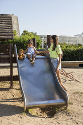 Mutter mit Tochter auf der Rutsche auf einem Spielplatz - MAUF02403