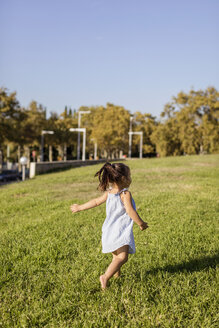 Rückansicht eines kleinen Mädchens, das auf dem Rasen in einem Park läuft - MAUF02415