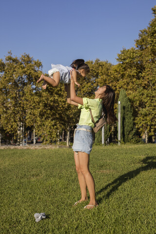 Happy mother playing with daughter in a park stock photo