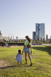 Mutter und Tochter gehen Hand in Hand in einem Park spazieren - MAUF02419
