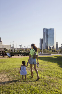 Mother and daughter walking hand in hand in a park - MAUF02419