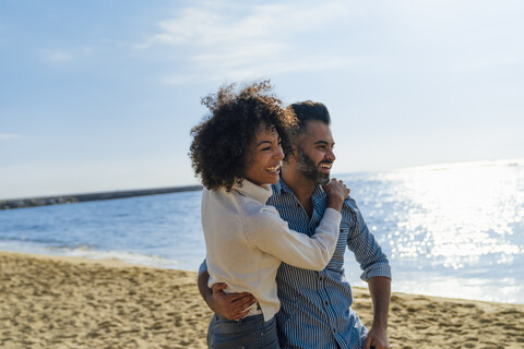 Spanien, Barcelona, glückliches Paar, das sich am Strand umarmt, lizenzfreies Stockfoto