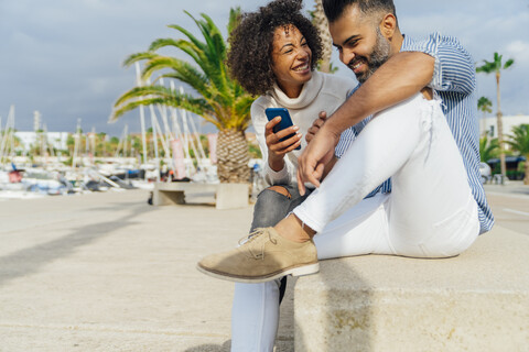 Spanien, Barcelona, glückliches Paar mit Handy am Yachthafen, lizenzfreies Stockfoto