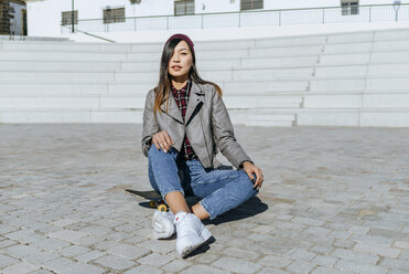 Portrait of young woman sitting on skateboard - KIJF02206
