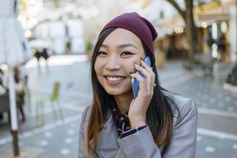 Porträt einer lächelnden jungen Frau am Telefon, lizenzfreies Stockfoto