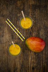 Mango and two glasses of Mango Lassi with curcuma and straws on wood - LVF07684