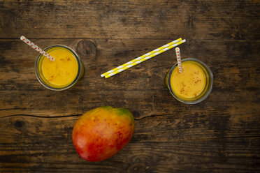 Mango and two glasses of Mango Lassi with curcuma and straws on wood - LVF07685