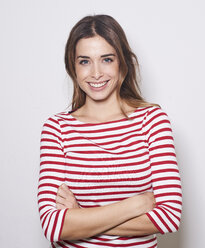 Portrait of smiling young woman wearing red-white striped shirt against light background - PNEF01165