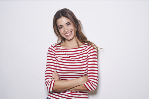 Portrait of laughing young woman wearing red-white striped shirt against white background - PNEF01166
