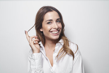 Porträt einer lachenden jungen Frau, die eine Haarsträhne zwirbelt - PNEF01171