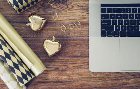 Bürotisch mit Laptop, Geschenkpapier, Büroklammer und goldenen Weihnachtskugeln, lizenzfreies Stockfoto