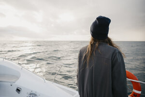 South Africa, young woman with woolly hat during boat trip at sunset - LHPF00385