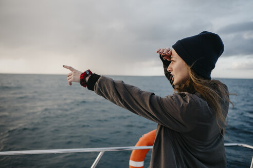 Südafrika, junge Frau mit Wollmütze während einer Bootsfahrt, mit dem Finger zeigend - LHPF00386
