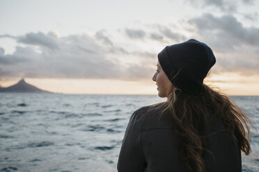 South Africa, young woman with woolly hat during boat trip at sunset - LHPF00391