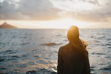 South Africa, young woman with woolly hat during boat trip at sunset - LHPF00393