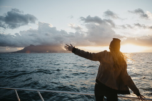 Südafrika, junge Frau mit Wollmütze während einer Bootsfahrt bei Sonnenuntergang - LHPF00394