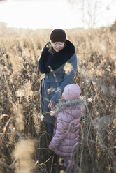 Kleines Mädchen steht Hand in Hand mit ihrer Mutter auf einer herbstlichen Wiese zur goldenen Stunde - PSIF00223