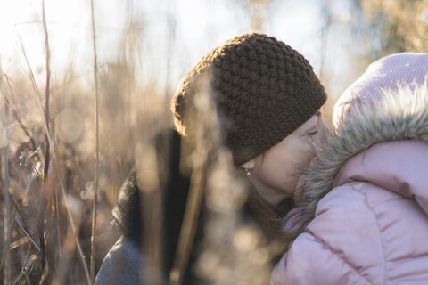 Frau und ihre kleine Tochter auf herbstlicher Wiese zur goldenen Stunde, lizenzfreies Stockfoto