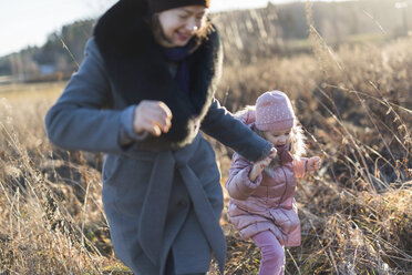 Kleines Mädchen läuft Hand in Hand mit ihrer Mutter auf einer herbstlichen Wiese zur goldenen Stunde - PSIF00227