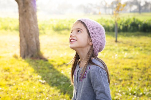 Porträt eines lächelnden Mädchens, das im Herbst auf einer Wiese steht und nach oben schaut - LVF07690