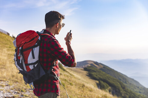 Italien, Monte Nerone, Wanderer auf dem Gipfel eines Berges, der mit einem Walkie-Talkie spricht - WPEF01299