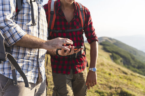 Italien, Monte Nerone, Nahaufnahme von zwei Männern beim Wandern und mit Smartphone in den Bergen - WPEF01300
