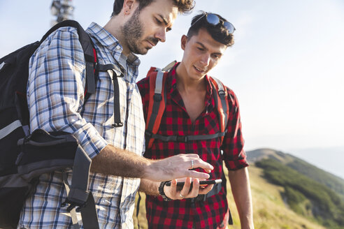 Italien, Monte Nerone, zwei Männer wandern und schauen in den Bergen auf ihr Smartphone - WPEF01301