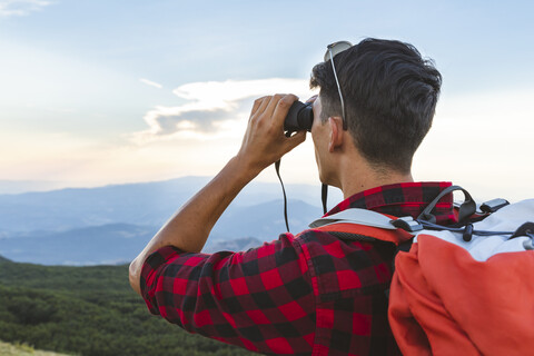 Italy, Monte Nerone, hiker in the mountains looking with binocular stock photo