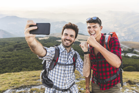 Italien, Monte Nerone, zwei glückliche Wanderer auf dem Gipfel eines Berges, die ein Selfie machen, lizenzfreies Stockfoto