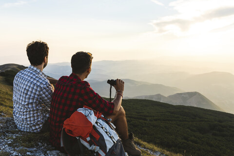 Italy, Monte Nerone, two hikers on top of a mountain enjoying the view at sunset stock photo