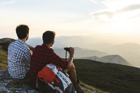 Italien, Monte Nerone, zwei Wanderer auf dem Gipfel eines Berges, die die Aussicht bei Sonnenuntergang genießen - WPEF01313